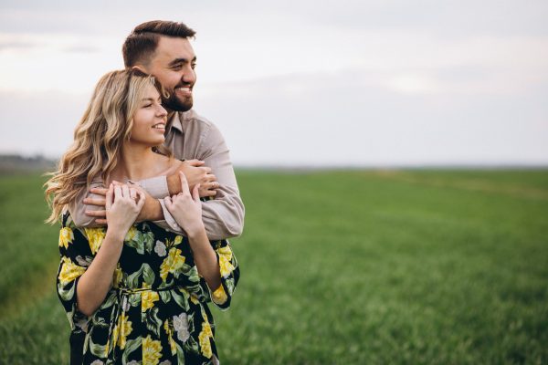 Young couple in the field with green grass